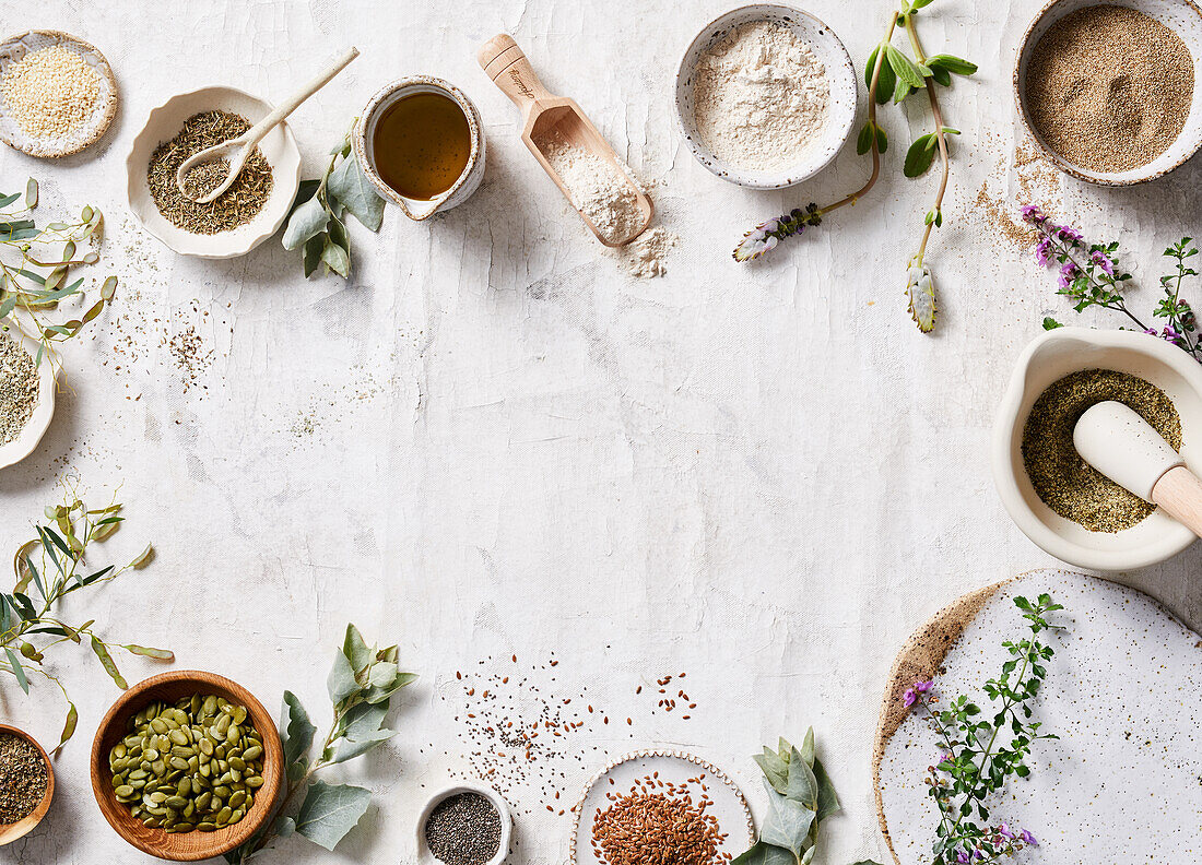 Top view composition of aromatic spices and herbs arranged on white table with fresh flowers