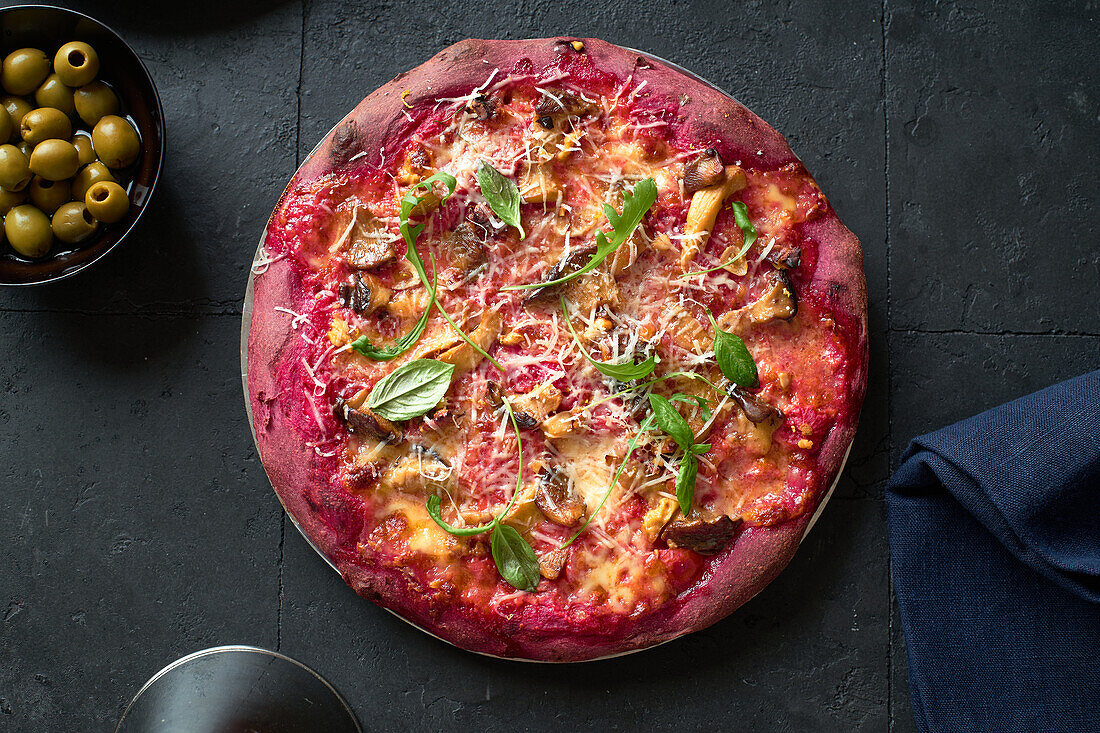 Purple colored rustic pizza with beetroot and vegetarian topping. Top view healthy food recipe