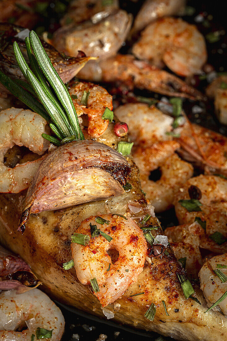 From above of black tray with appetizing baked swordfish served with prawns and confit garlic