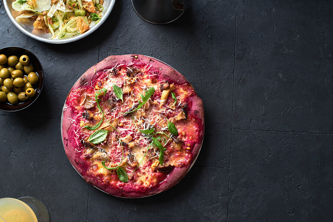 Purple colored rustic pizza with beetroot and vegetarian topping. Top view healthy food recipe