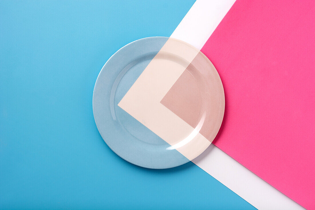 Draufsicht auf einen Teller mit weißer Linie und mit blauen und rosa Farben auf einem Tisch in derselben Farbe
