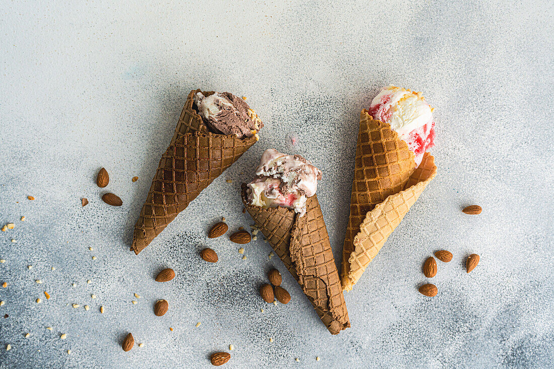 From above waffle cones with cherry and chocolate ice cream on concrete background