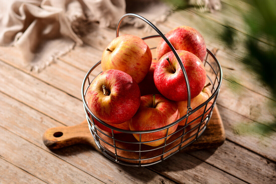 From above of tasty ripe apples in metal basket on chopping board in countryside on sunny day