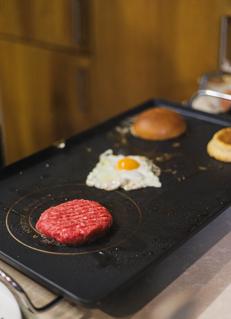 Ingredients for delicious hamburger on electric grill in kitchen