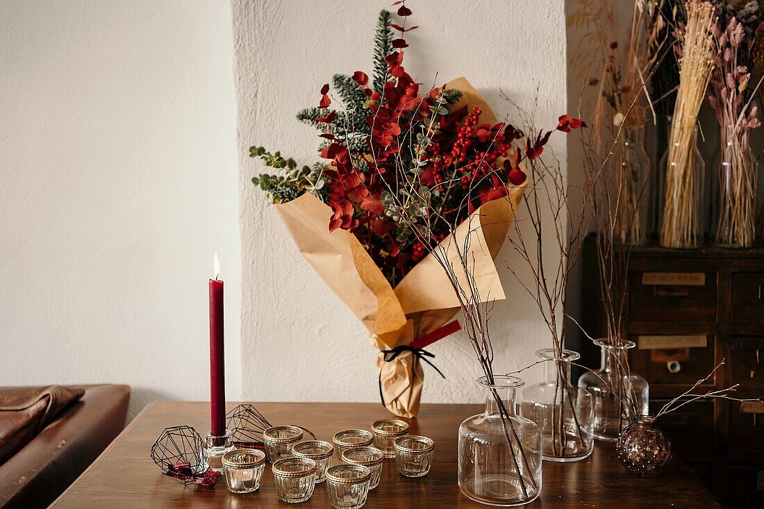 Stylish Christmas bouquet placed on festive table against light wall in room in daylight