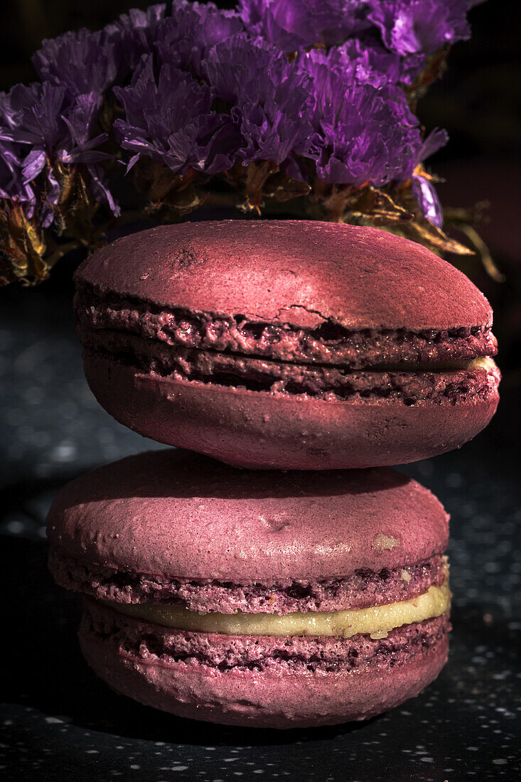 Pair of delicious sweet macaroons of purple color stacked together on sunlit table in morning