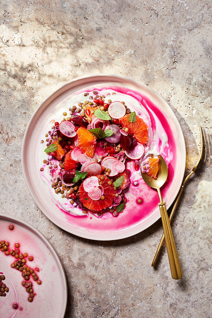 Top view of plate with delicious bright Italian salad made of vegetables and fruits served on table with sauce and gold silverware