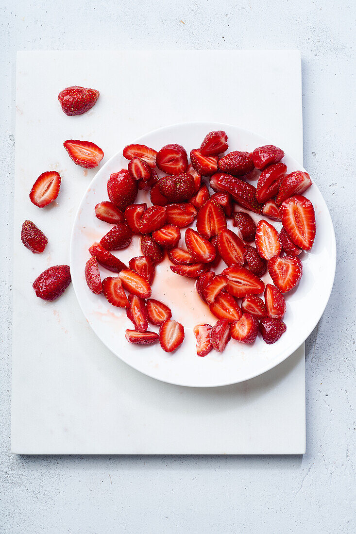 In Scheiben geschnittene Erdbeeren mit Zucker überzogen auf einem Teller. Kochen von Dessert oder Marmelade