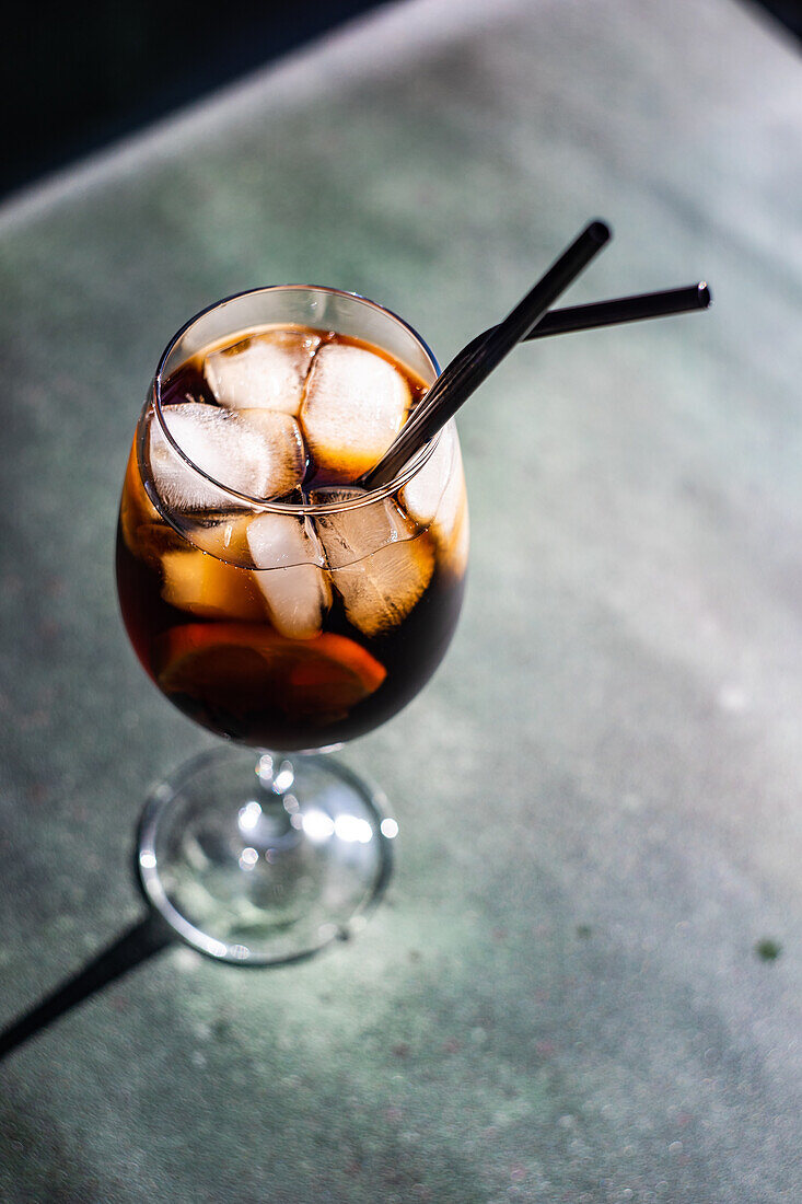 Alkoholcocktail Cuba Libre mit Orangenscheibe und Eis im Glas