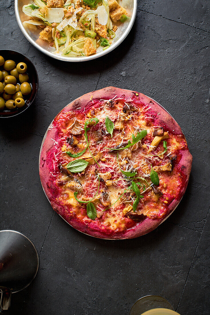 Purple colored rustic pizza with beetroot and vegetarian topping. Top view healthy food recipe