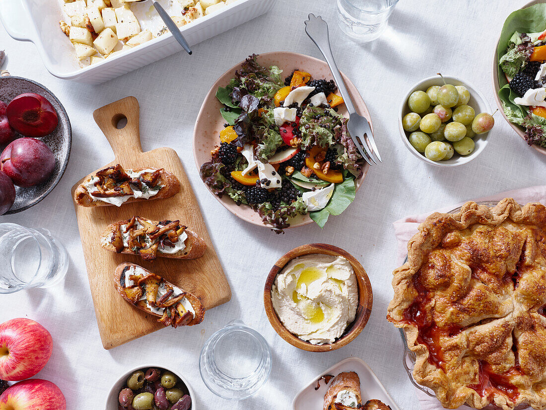 Vegetarian dinner with various snacks and dishes: salad plates, bruschetta, roasted vegetables and a pie