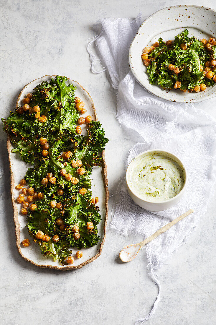 Leckeres gesundes Mittagessen mit Brokkoli und Kichererbsen auf Tellern neben einer Schüssel mit leckerem Hummus auf dem Küchentisch von oben