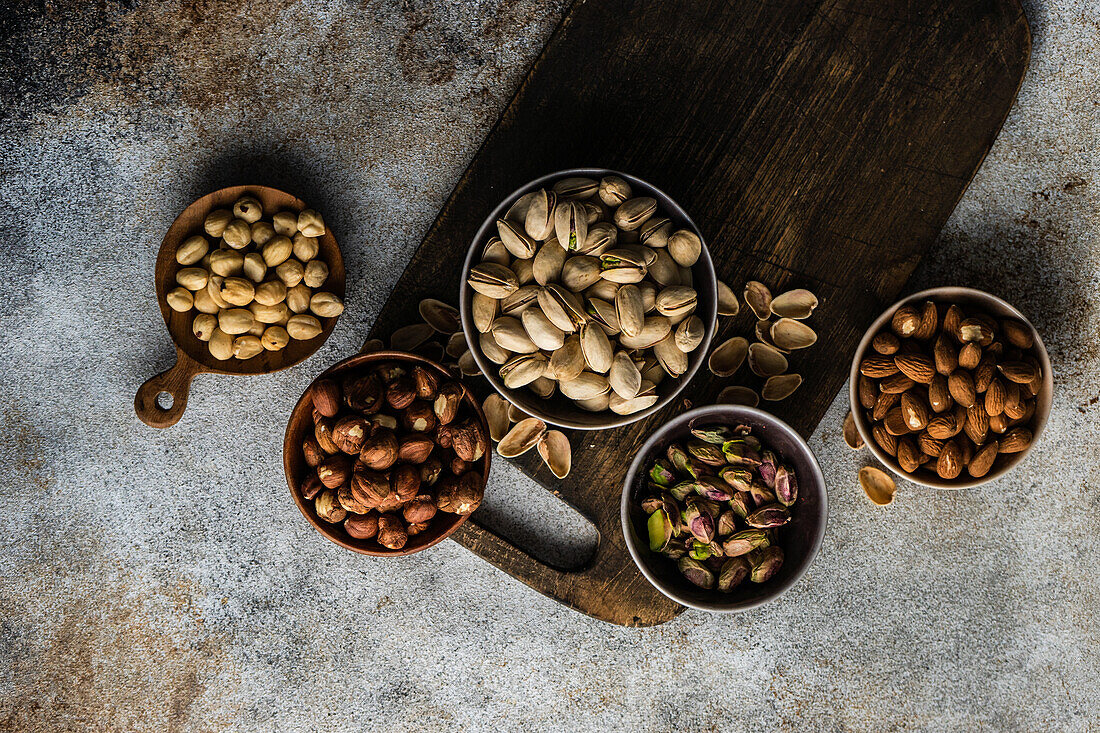 From above bowls with different kinds of nuts on concrete table background