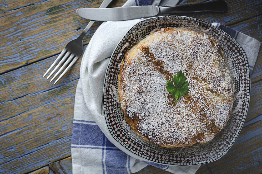 Draufsicht auf eine appetitliche Bastilla mit aromatischen Gewürzen auf einem Tisch in der Nähe eines Blumenzweigs während des Ramadan-Festes