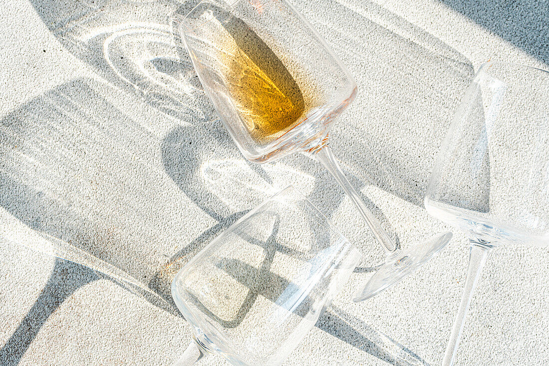 Von oben flach liegende Weingläser mit verschiedenen Arten von trockenem Weißwein auf grauem Betonhintergrund mit tiefen Schatten