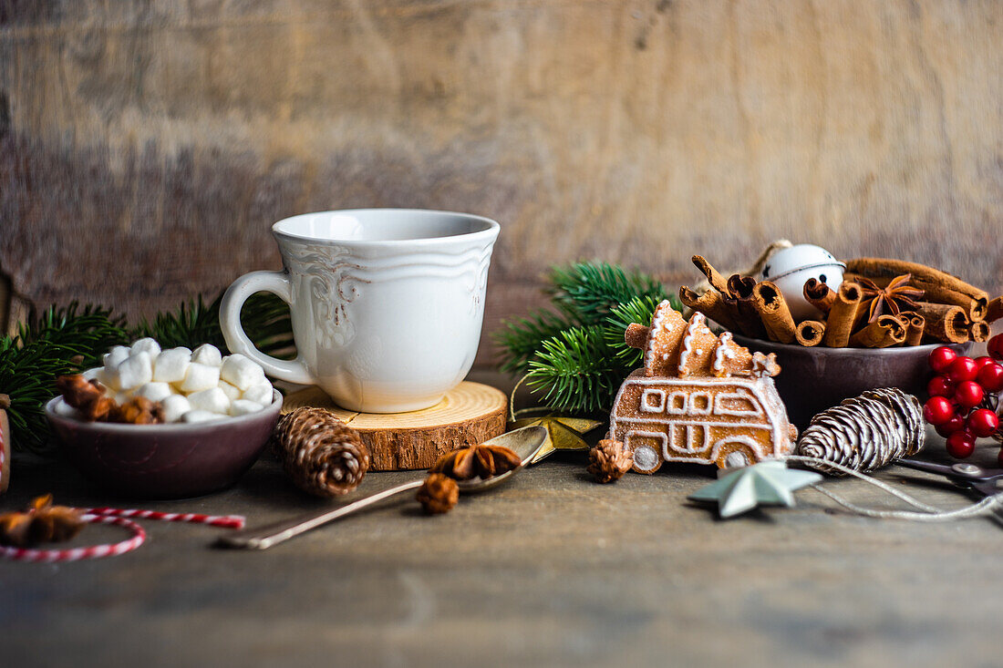 Becher mit Heißgetränk und Mini-Marshmallows mit Gewürzen auf weihnachtlich dekoriertem Hintergrund