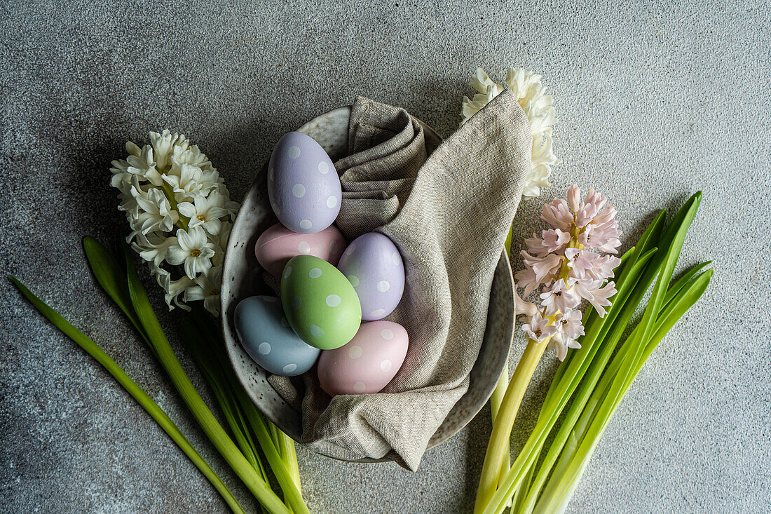 From above spring table setting with hyacinth flowers and colored eggs on grey concrete table for festive dinner