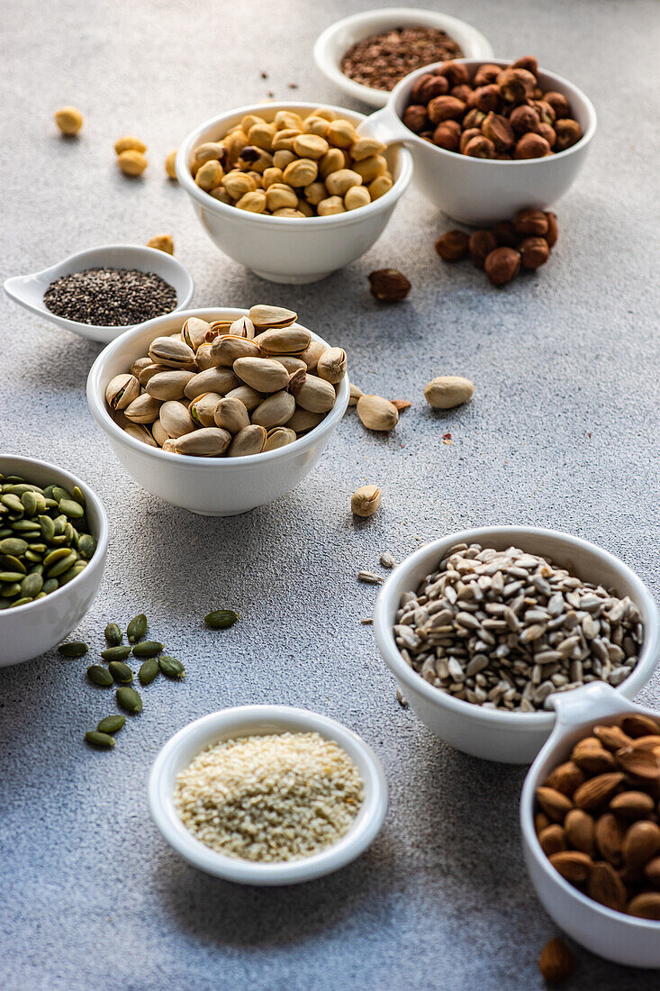 From above bowls full of nuts and seeds on concrete background