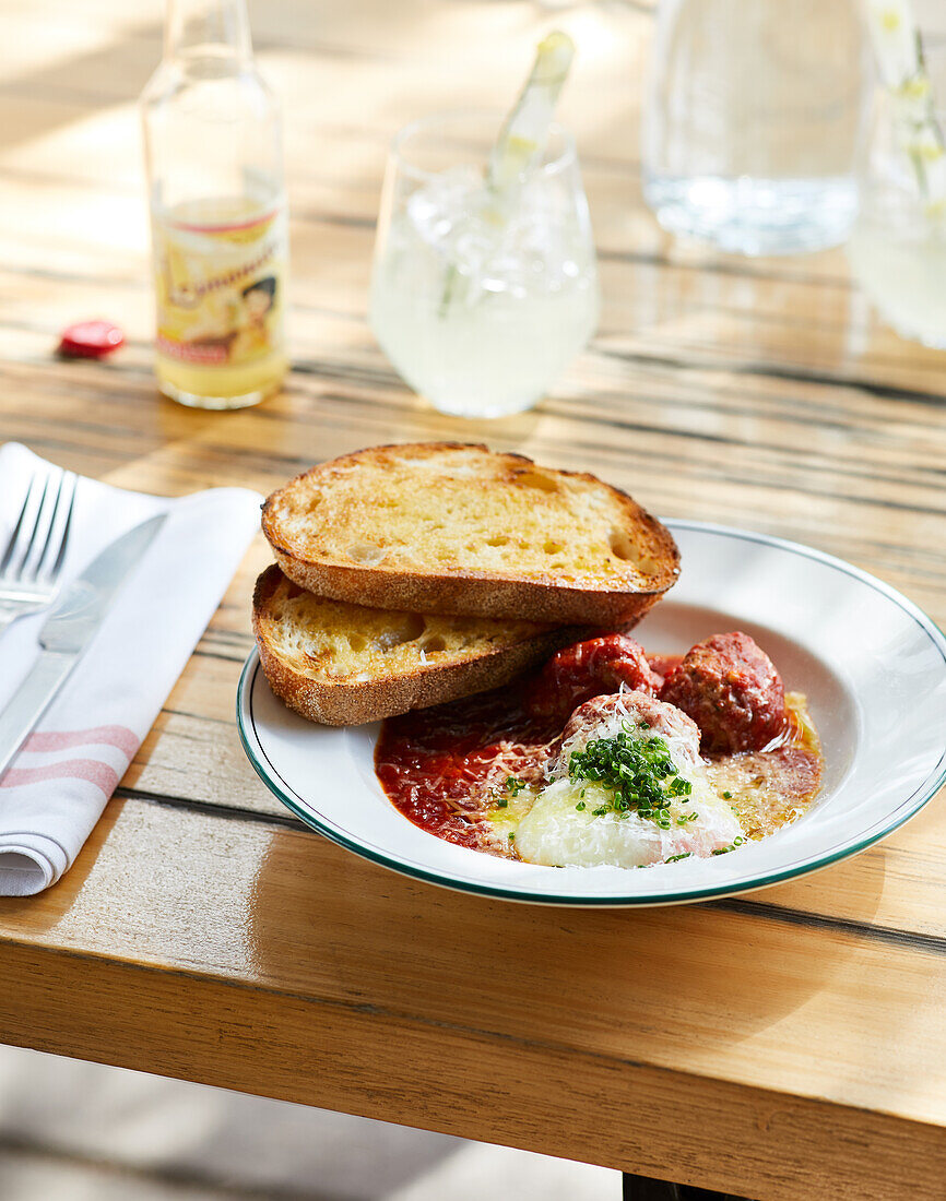 Appetizing tomato soup with meatballs served on plate with bread and herbs in restaurant