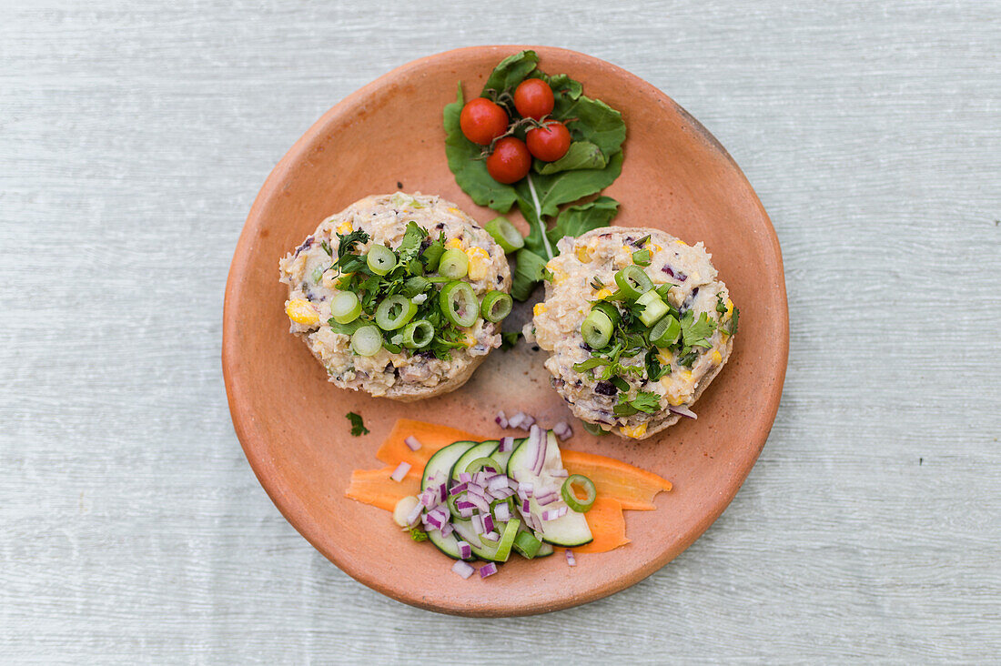 Draufsicht auf appetitliche Sandwiches mit Pilzpastete und Gemüse, serviert auf einem Holzteller auf einem Tisch für ein vegetarisches Mittagessen