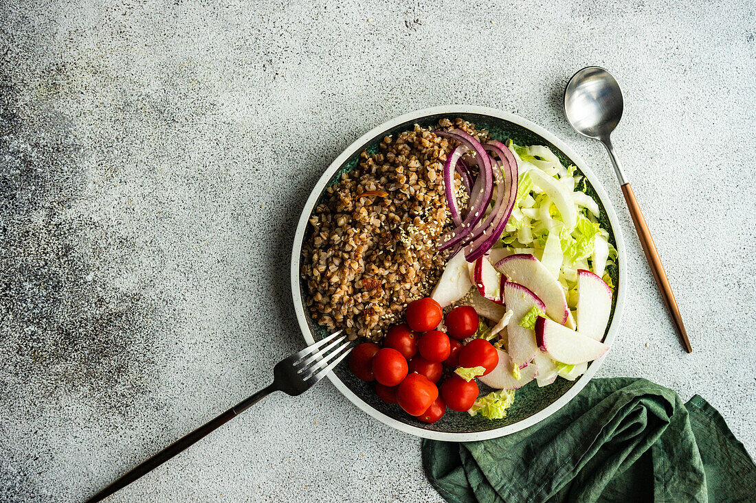 From above bowl with buckwheat and vegetables served on concrete grey table