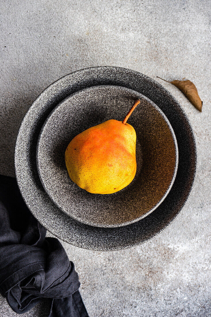From above ceramic bowl with organic pears fruit on concrete surface