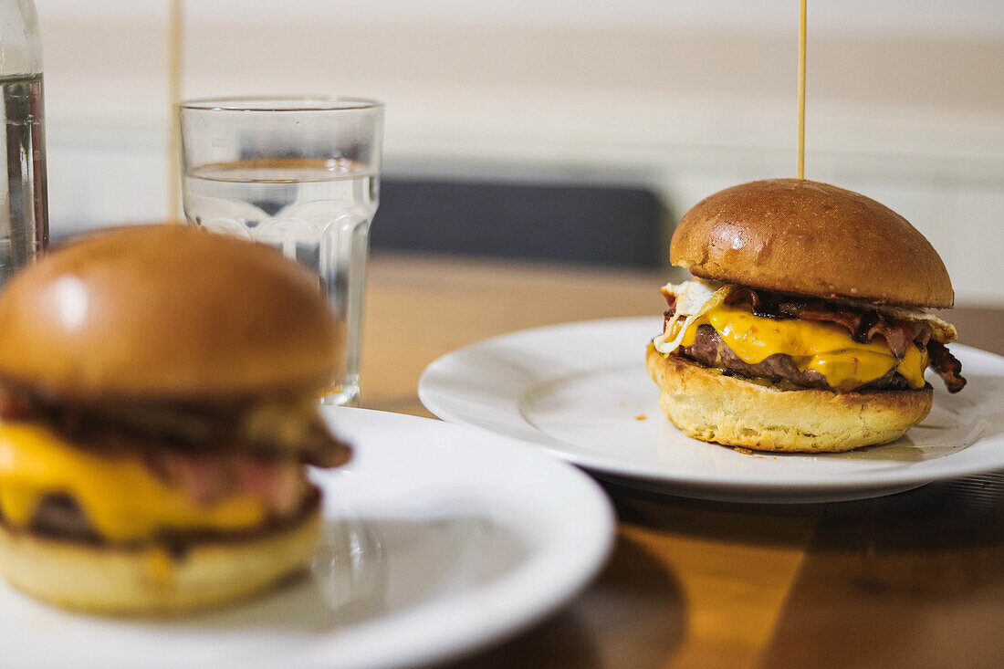 Scrumptious hamburger with toothpick while serving on white plate placed on table