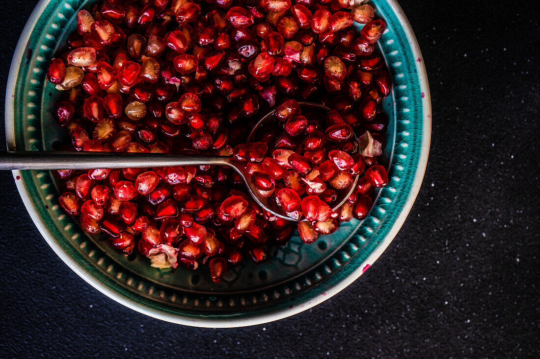 From above ripe organic pomegranate fruit seeds in ceramic plate