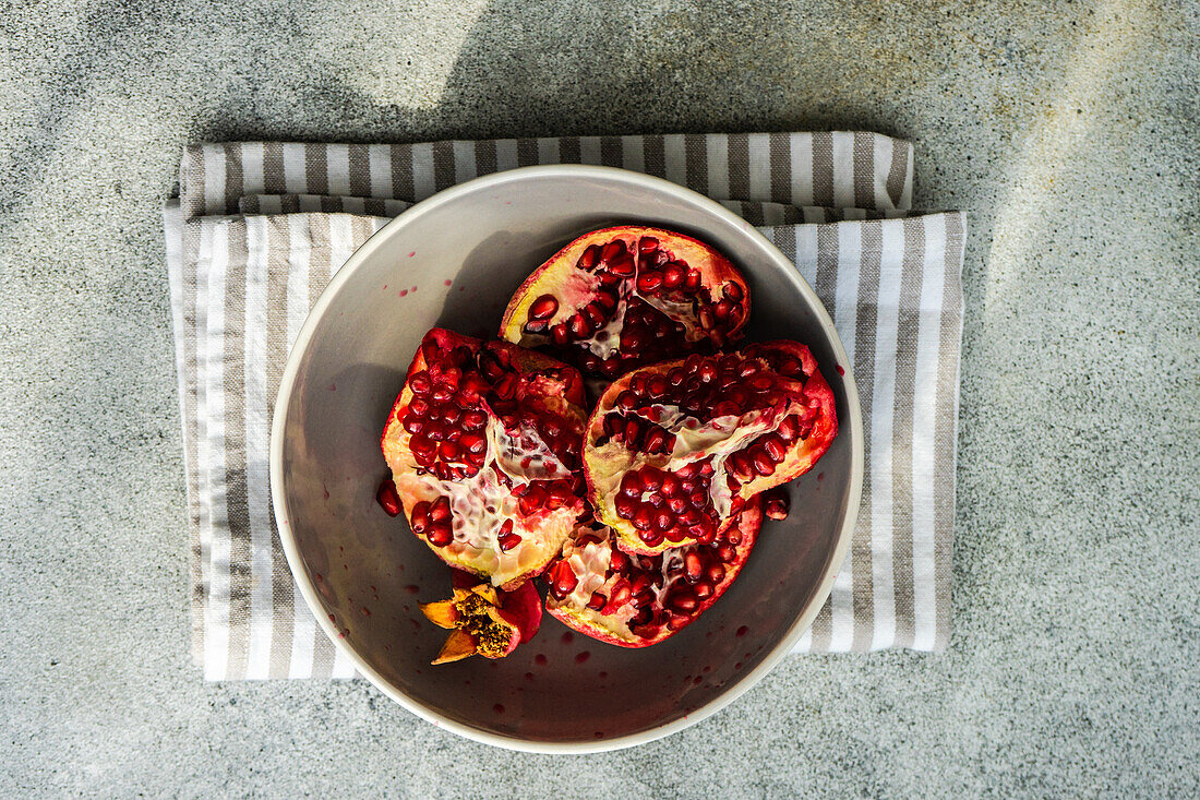 From above ripe organic pomegranate fruit on the ceramic plate and tea towel