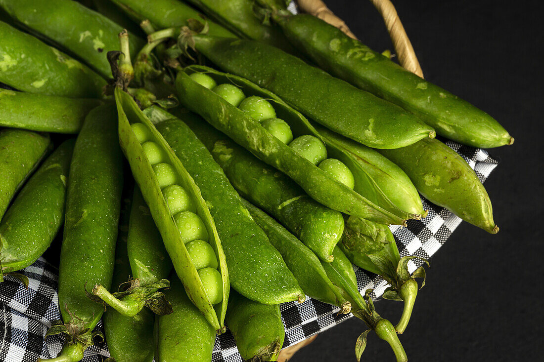 From above pile of ripe whole and opened pods with peas placed together in basket