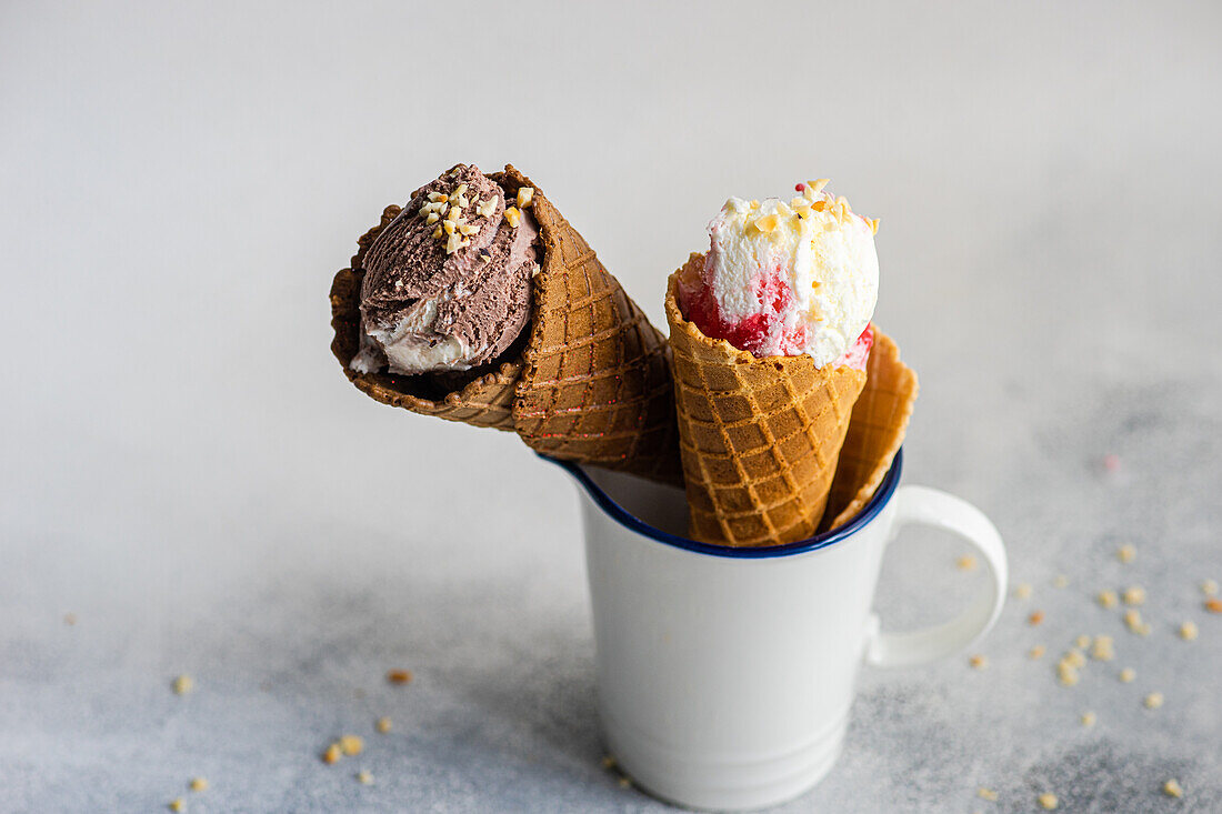 White cup with waffle cones filled with ice cream on concrete table