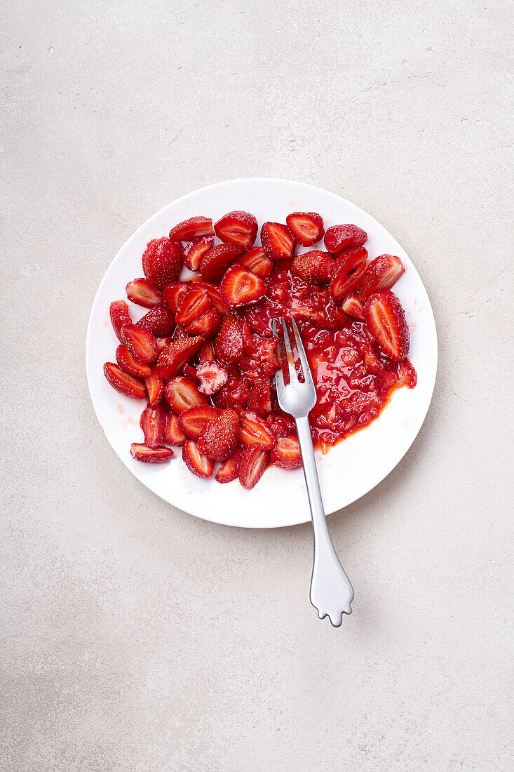 In Scheiben geschnittene Erdbeeren mit Zucker überzogen auf einem Teller. Kochen von Dessert oder Marmelade