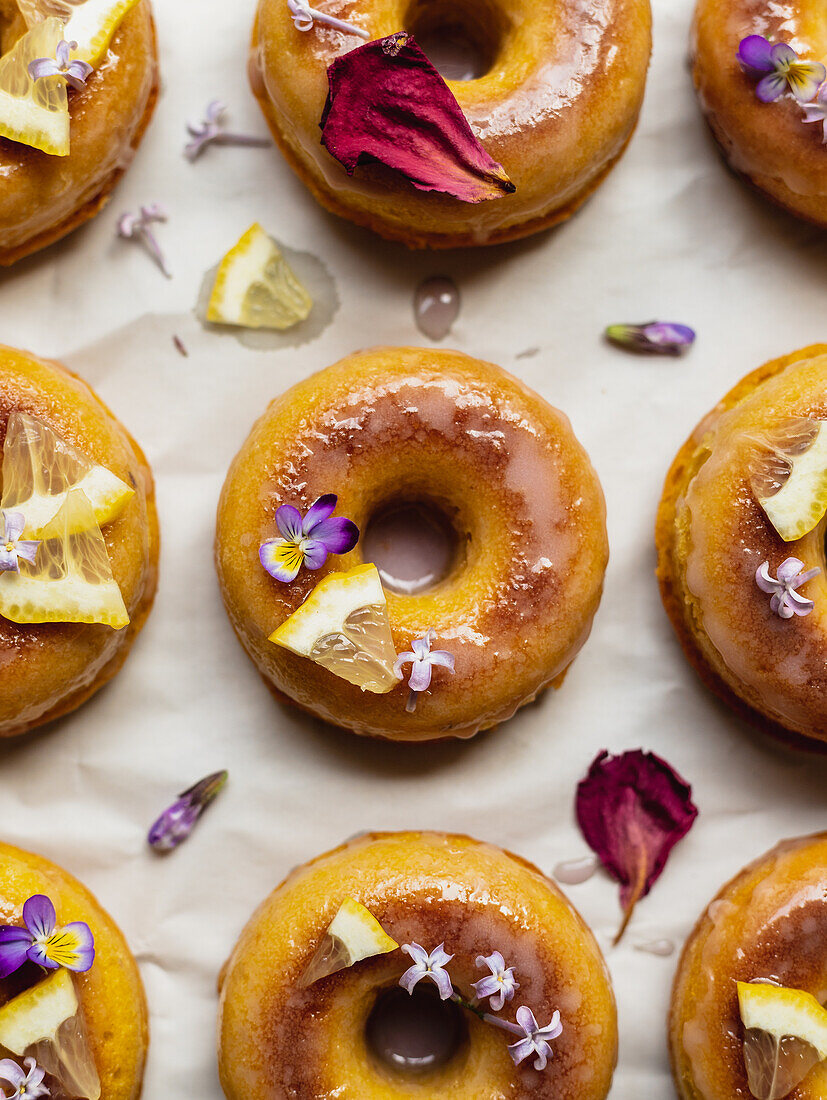Draufsicht auf leckere Donuts auf Kühlregal mit Blättern zwischen blühenden Lavendelzweigen auf Marmoroberfläche