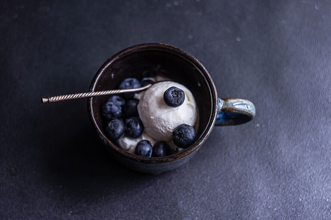 Von oben Schüssel voll mit köstlichen reifen Blaubeeren auf schwarzem Hintergrund platziert