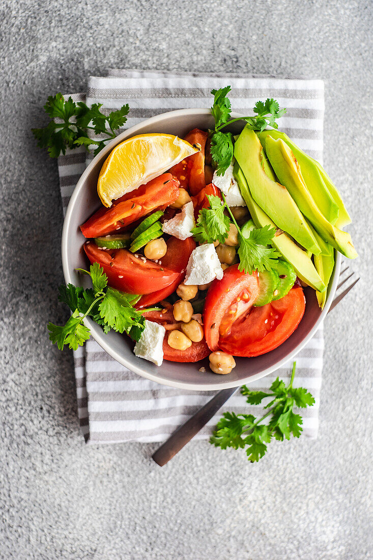 From above healthy salad with organic seasonal vegetables and avocado served on concrete table