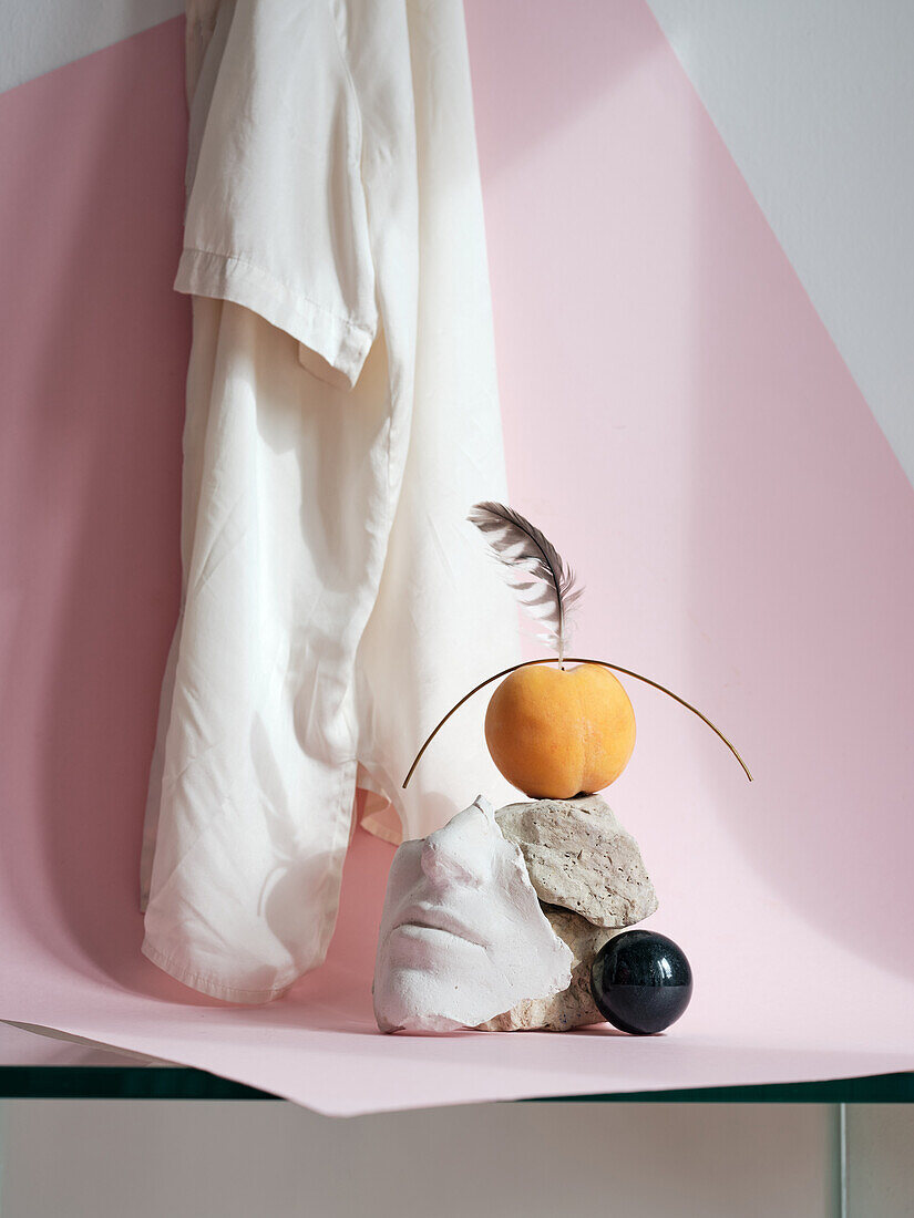 Still life on ceramic face with peach and stones on pink background