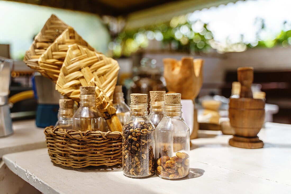 Selektiver Fokus auf kleine verkorkte Plastikflaschen mit Kaffeekörnern, die auf dem Tisch neben einem Weidenkorb mit transparenten Behältern stehen