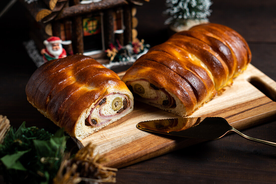 Von oben köstlicher gebackener Schinken und Olivenbrot, serviert in einer Bäckerei auf einem Schneidebrett auf dem Tisch