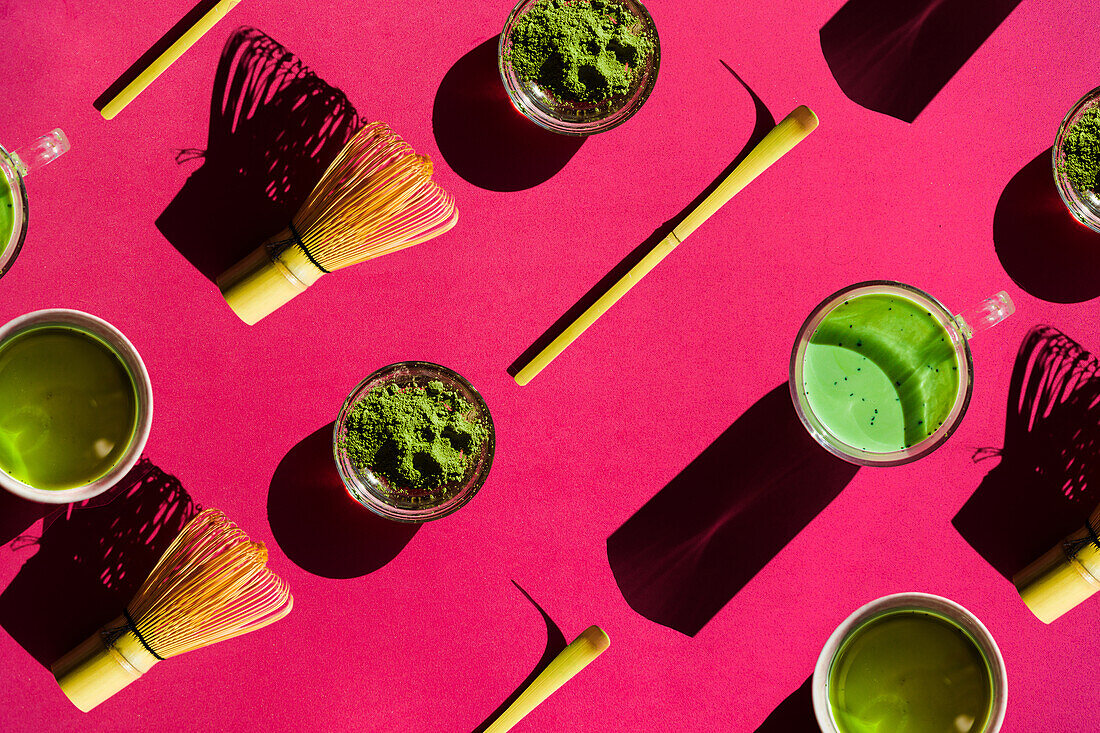 Draufsicht Vollbild heller Hintergrund von Glas mit grünem Tee und getrocknetem Matcha mit Bambus-Chasen und Chashaku auf rosa Oberfläche