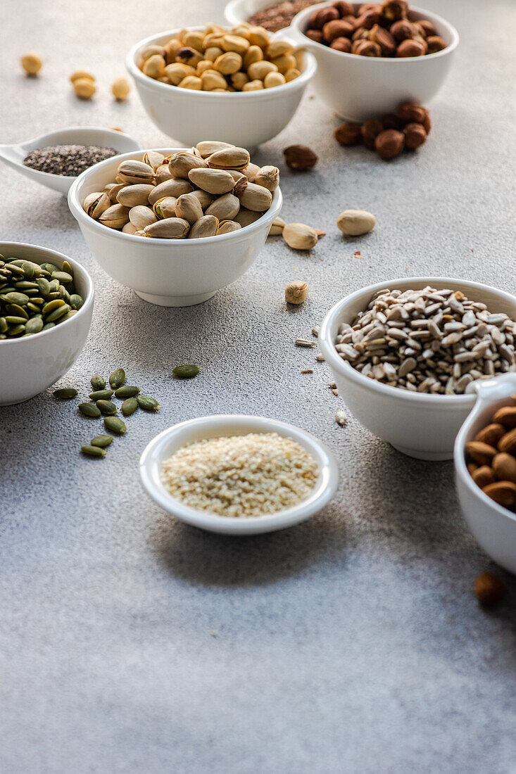 From above bowls full of nuts and seeds on concrete background