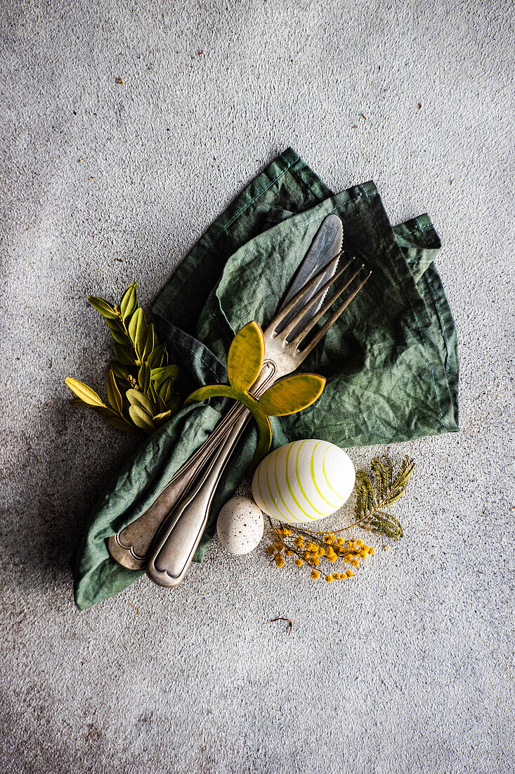 From above place setting for Easter dinner in green color on concrete background