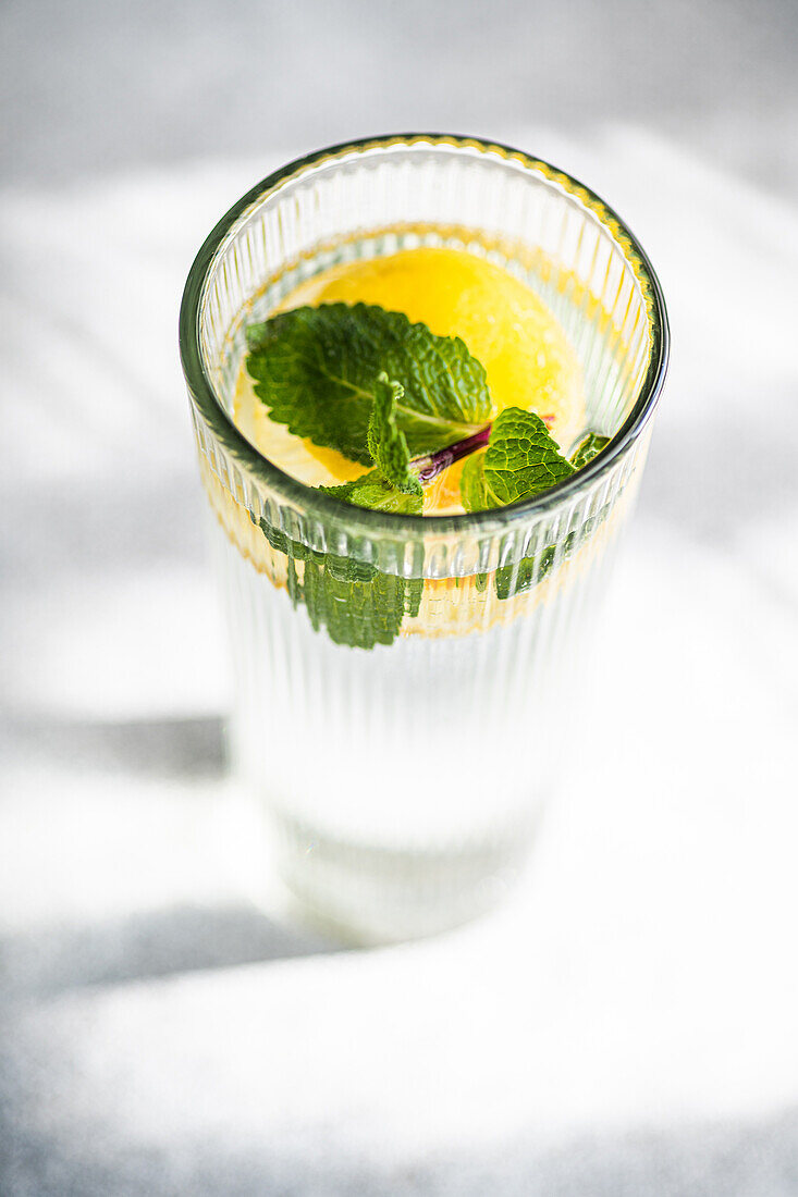 Mojito-Cocktail mit Minze und Zitrone, serviert in einem Kristallglas auf einem Betontisch