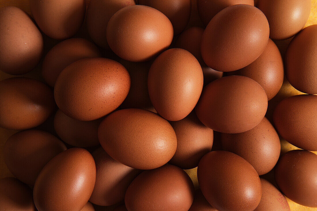 From above of full frame background of heap of raw brown chicken eggs