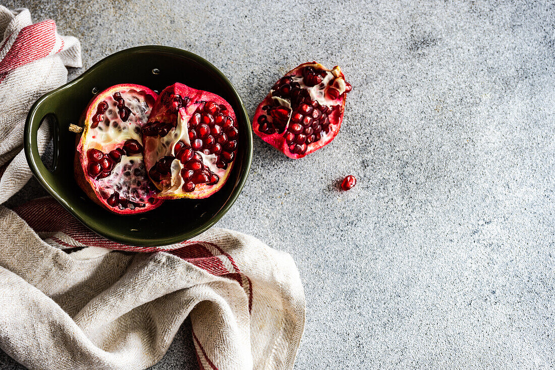 Organic ripe pomegranate fruit in ceramic bowl on stone background