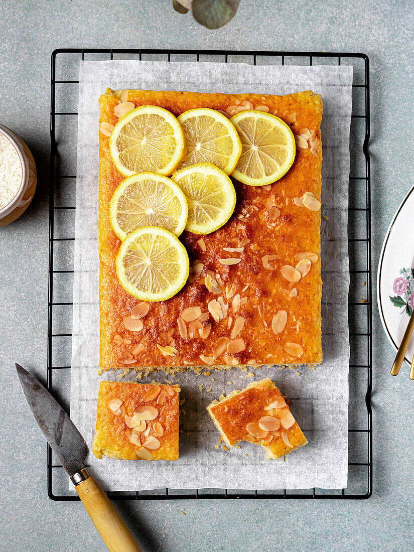 Square slice of tasty homemade lemon cake placed on metal rack in kitchen on grey background