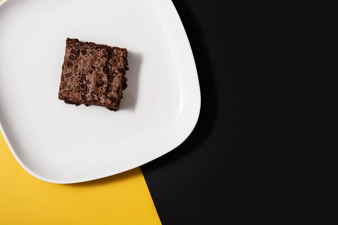 Stück frischer Brownie auf schwarzem und gelbem Hintergrund