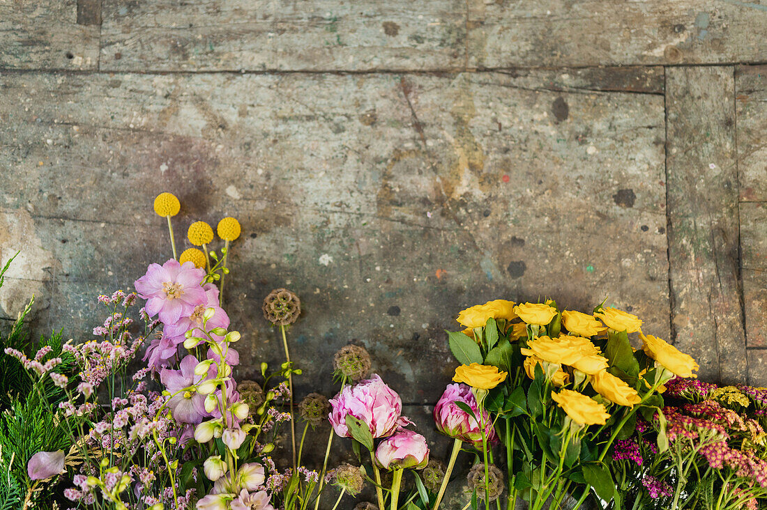 Draufsicht auf verschiedene frische bunte Blumen, die in einer Reihe auf einem alten Tisch in einem Blumenladen stehen