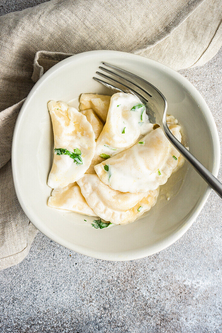From above traditional ukrainian dumplings stuffed with potato, well-known vareniki, served in a bowl with sour cream
