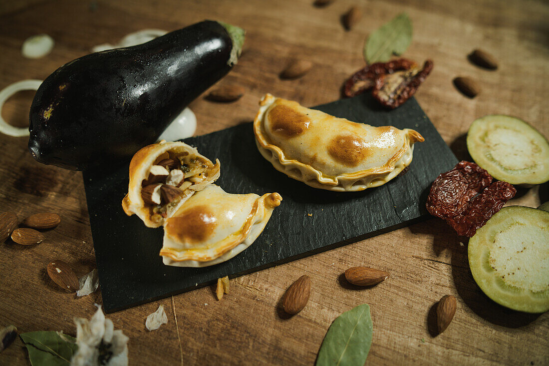 From above of appetizing argentinian empanadas served on flat plate on wooden table near ingredients in kitchen