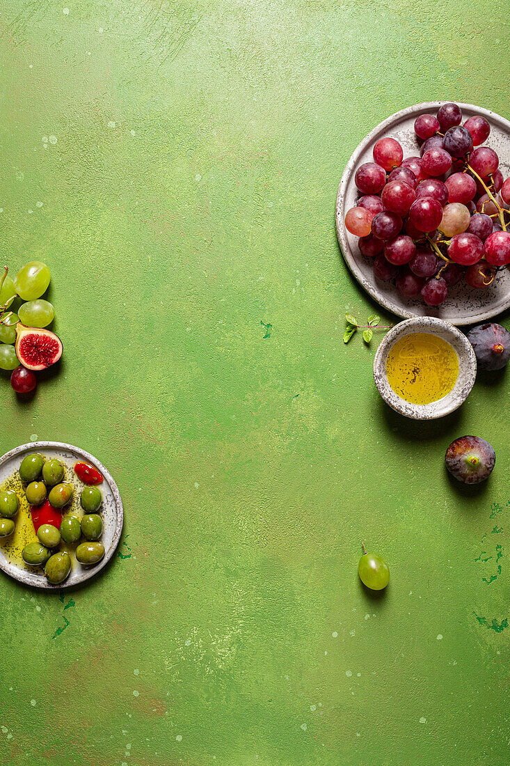 Top view of bunch of delicious fresh juicy red and green grapes served on plate on green background